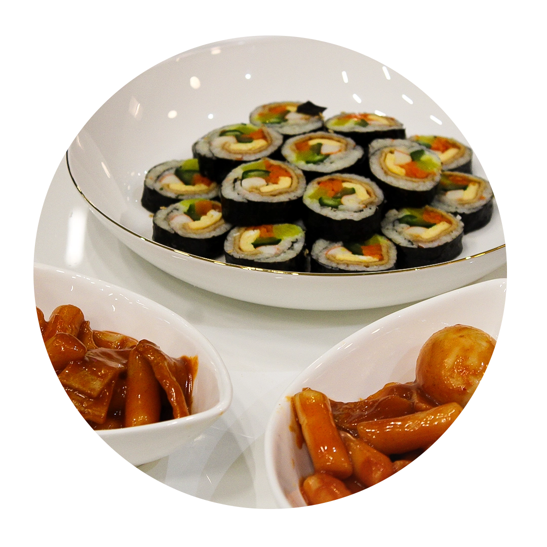 Plate of kimbap with two bowls of tteokbokki