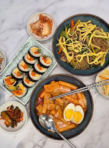 Delicious Korean meal featuring kimbap, tteokbokki, and japchae.